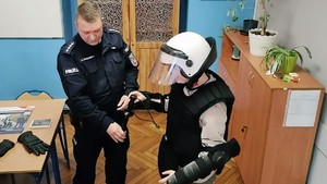 Zdjęcie przedstawia policjanta oraz uczennicę przebraną w policyjny strój