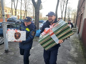 Zdjęcie przedstawia policjantów i strażników miejskich niosących prezenty
