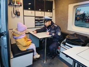 Zdjęcie przedstawia policjanta opowiadającego dziecku o swojej pracy