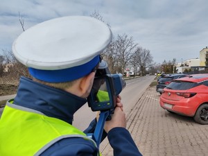 Zdjęcie przedstawia policjanta podczas pomiaru prędkości
